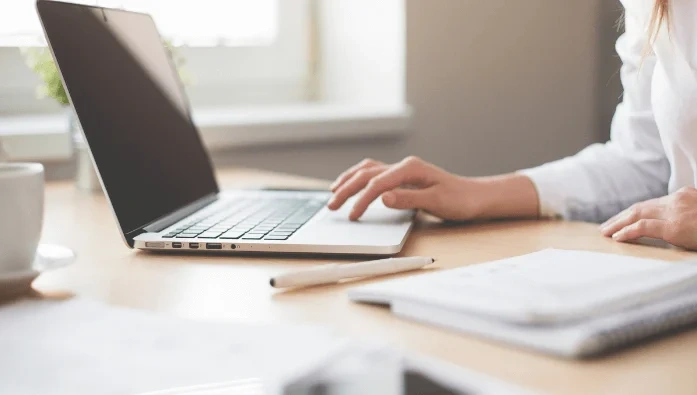 Main d’un secrétaire du CSE travaillant sur un ordinateur portable avec carnet de notes