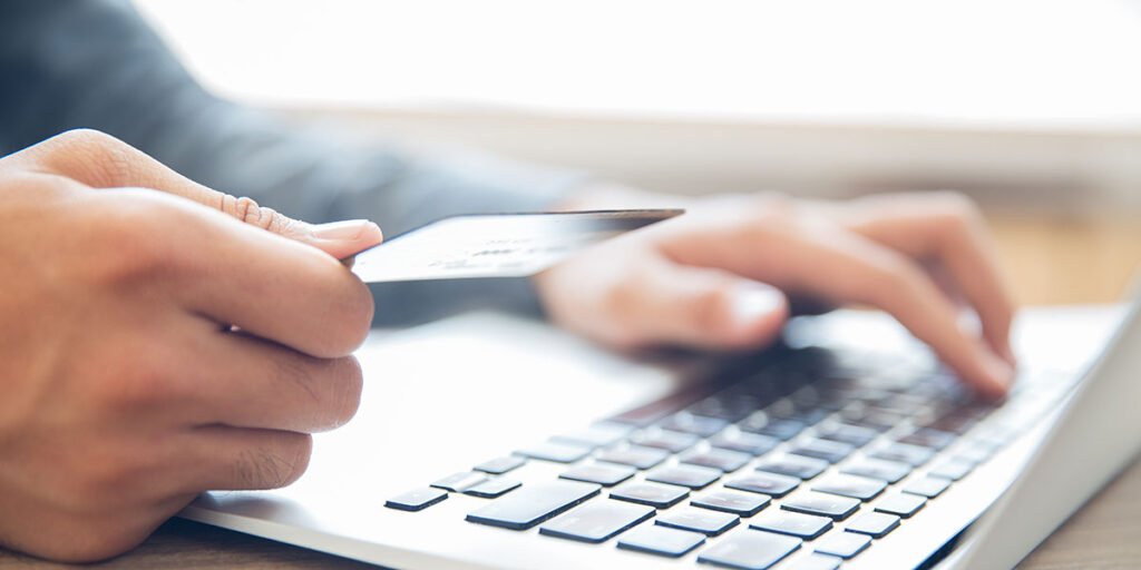 Main tenant une carte bancaire devant un clavier d’ordinateur pour un paiement en ligne SEPA